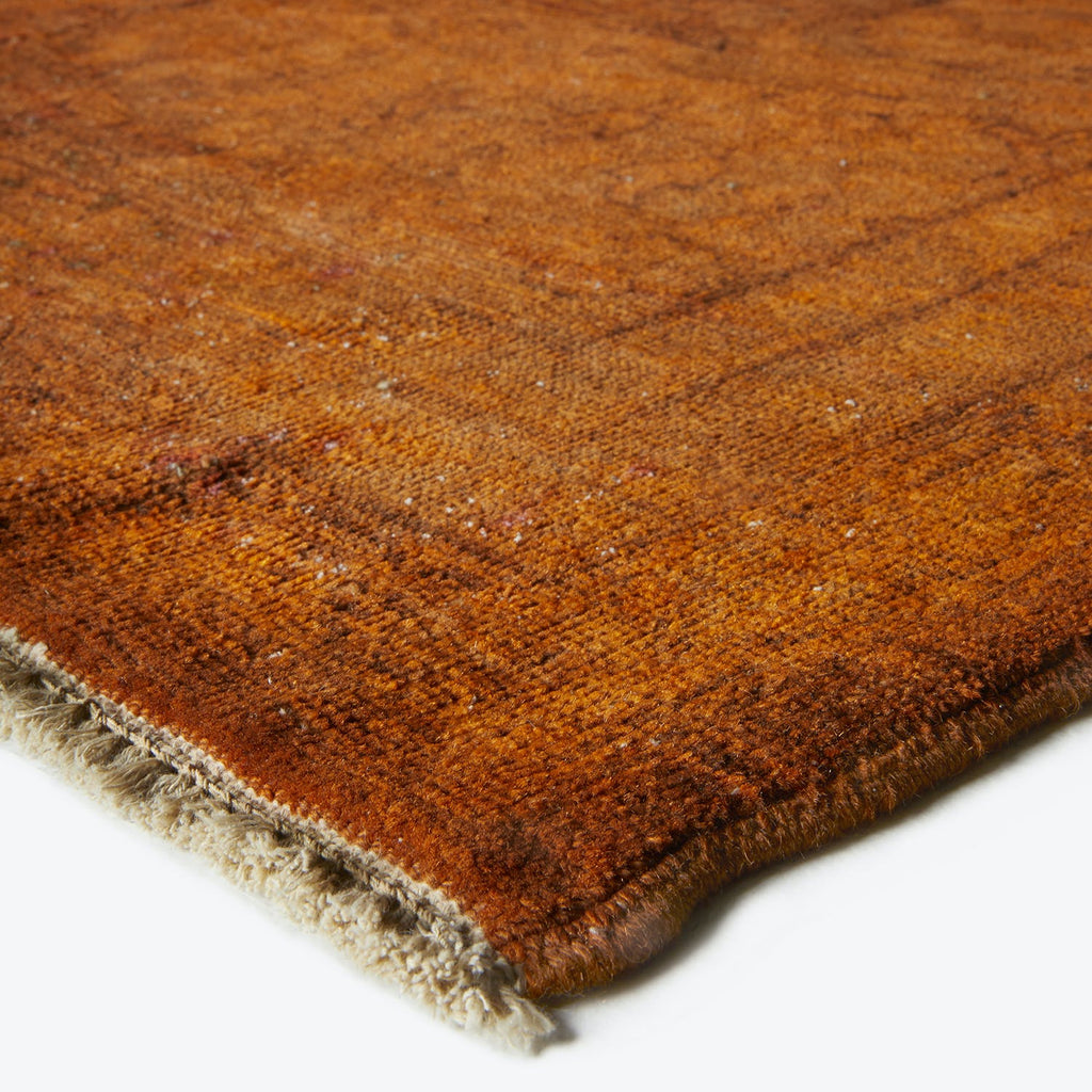 Close-up of a high-quality hand-woven rusty orange rug with fringes.