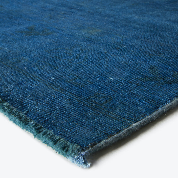 Close-up of a durable, hand-woven deep blue rug with fringe.
