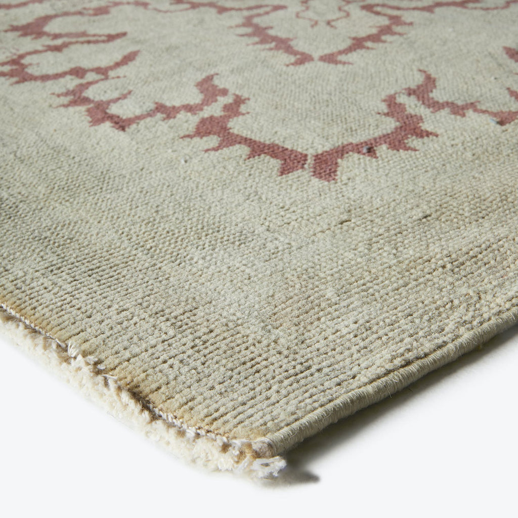 Close-up view of a light-colored, thick-piled rug with ornamental pattern.