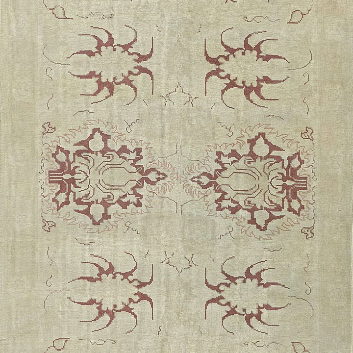 Elegant vintage rug with symmetrical burgundy designs, inspired by Oriental motifs.