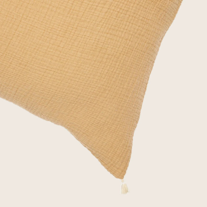 Cozy mustard-yellow cushion with textured surface and delicate tassel.