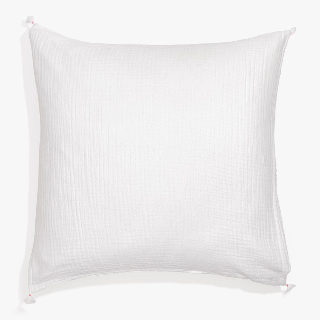 White square pillow with waffle-like weave and pink pom-pom corners.