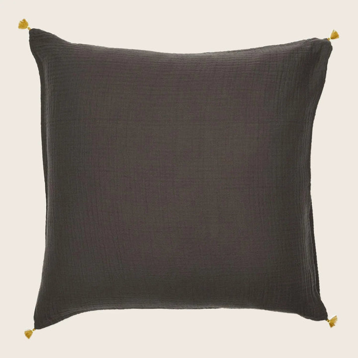 Square-shaped dark pillow with woven texture and gold tassel embellishments.