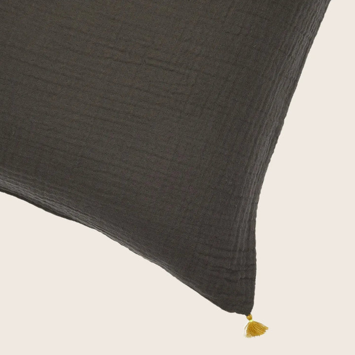 Close-up of textured dark cushion with gold tassel detail.