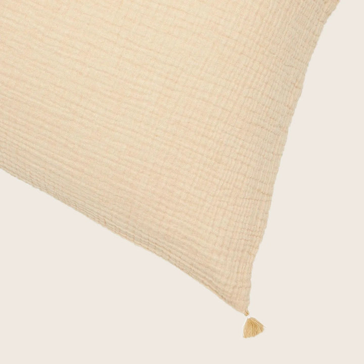 Close-up of a textured cream cushion with a tassel attachment.