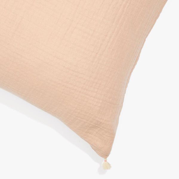 Blush pink linen cushion with crinkled texture and decorative tassel.