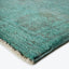 Close-up view of a plush turquoise rug with distressed pattern.
