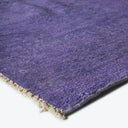 Vibrant purple rug with plush texture and woven backing revealed.