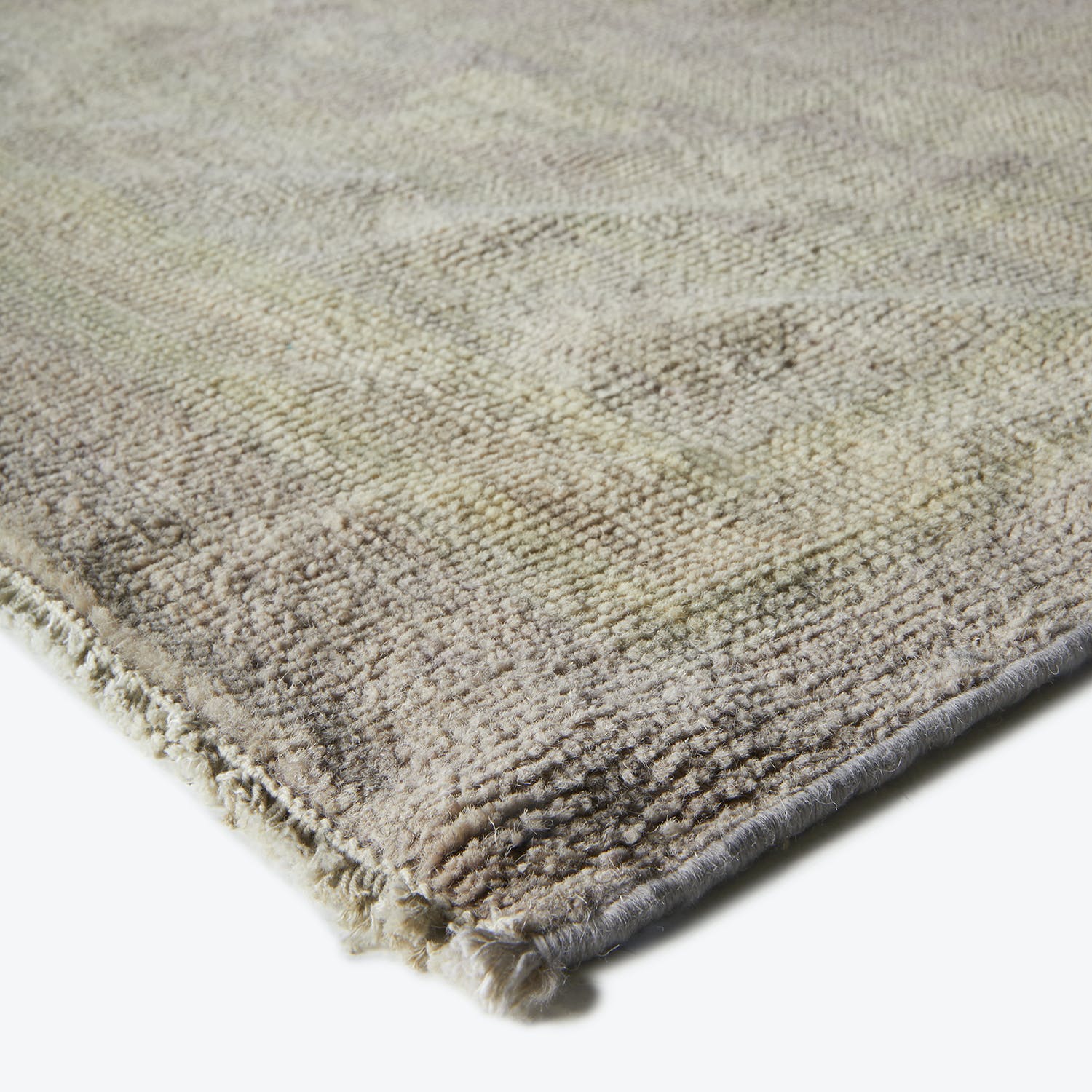 Top-down view of a plush, textured rug with muted hues.