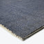 Close-up view of a plush, textured dark blue carpet corner.