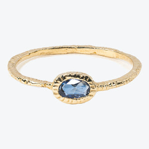 Elegant gold ring with bezel-set blue gemstone, textured frame. - hover