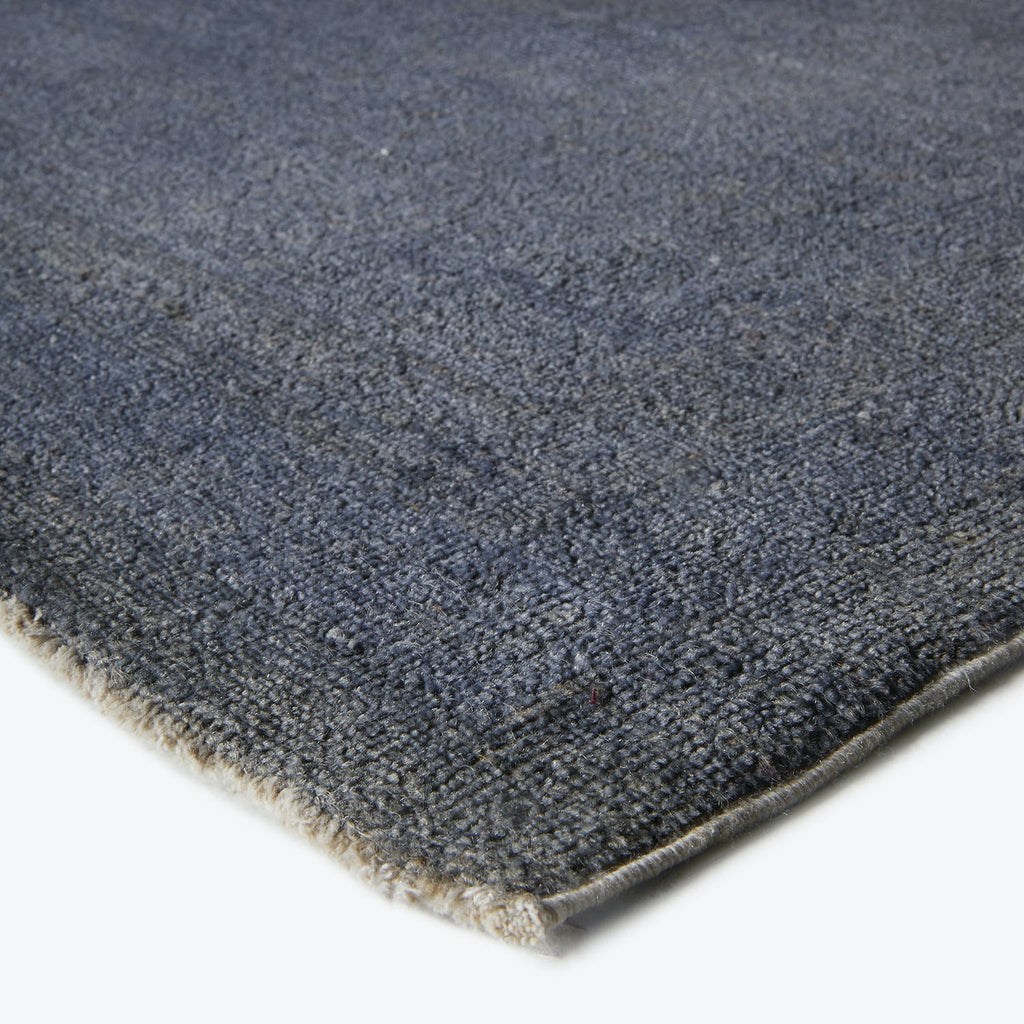 Close-up of dense, plush blue carpet with hemmed edge.