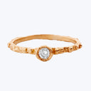 An elegant gold band ring with a textured surface and diamond centerpiece.