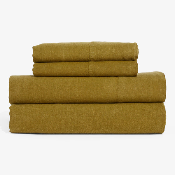 Neatly folded mustard green linens stacked in different sizes.