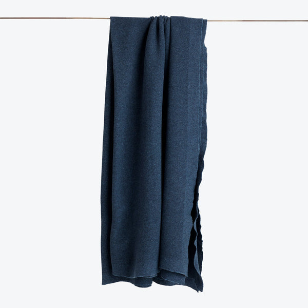 Blue denim fabric hangs from a brown rod against white background.