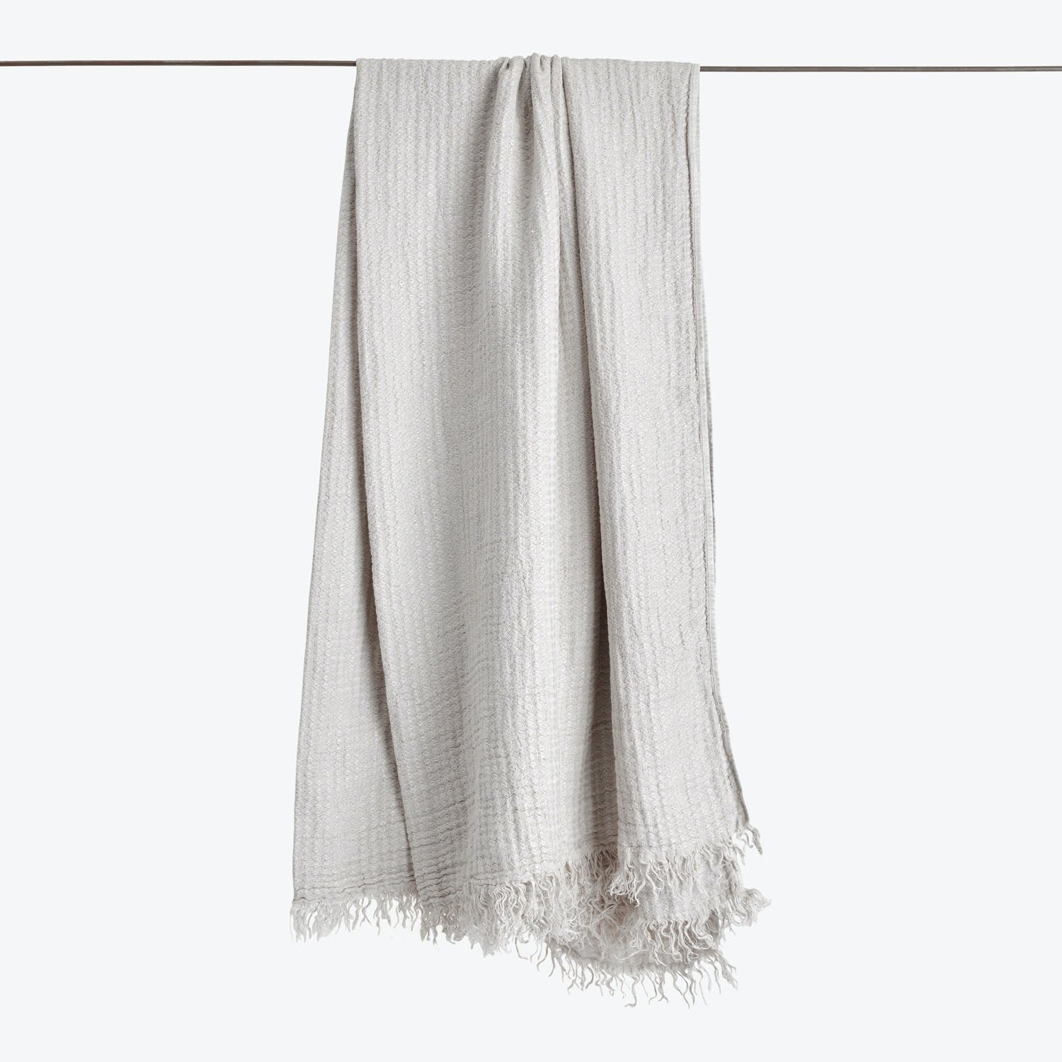Light-colored fabric with subtle pattern and fringe detailing, hanging vertically.