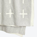Close-up of heather gray fabric with white cross patterns (+).