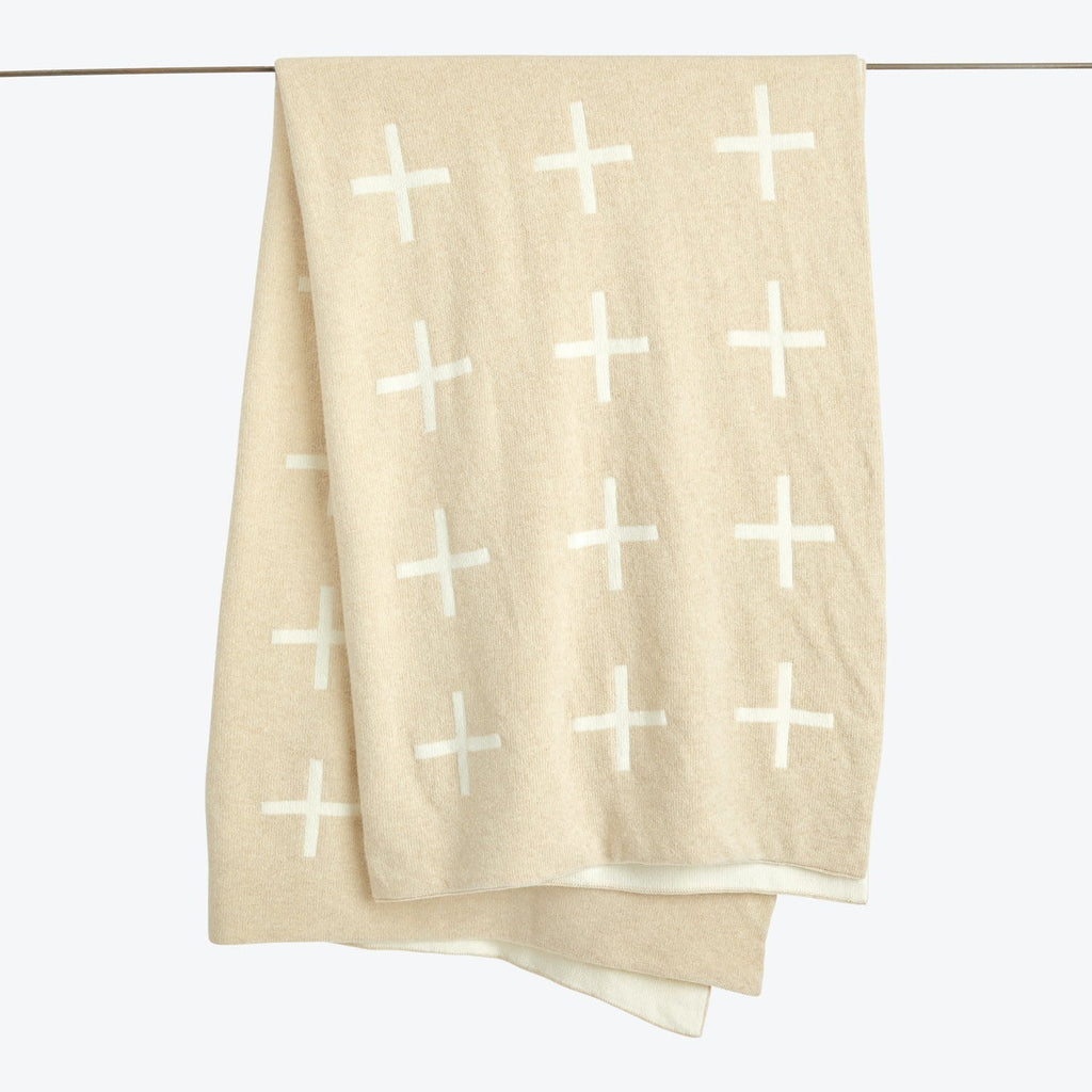 A beige towel with white cross pattern hangs on a rod.