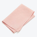 Neatly folded light pink fabric with frayed edges on white background.