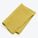 Neatly folded yellow cloth with textured surface on white background.