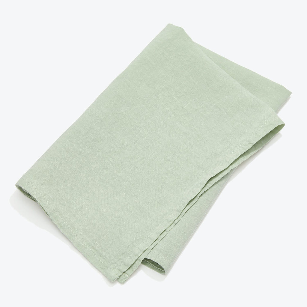 Neatly folded pale green linen fabric on white background.