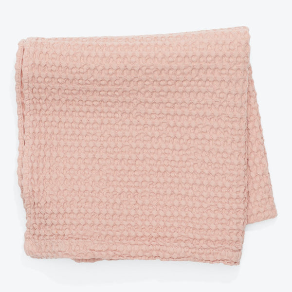 Soft pink blanket with textured pattern, perfect for cozy evenings.