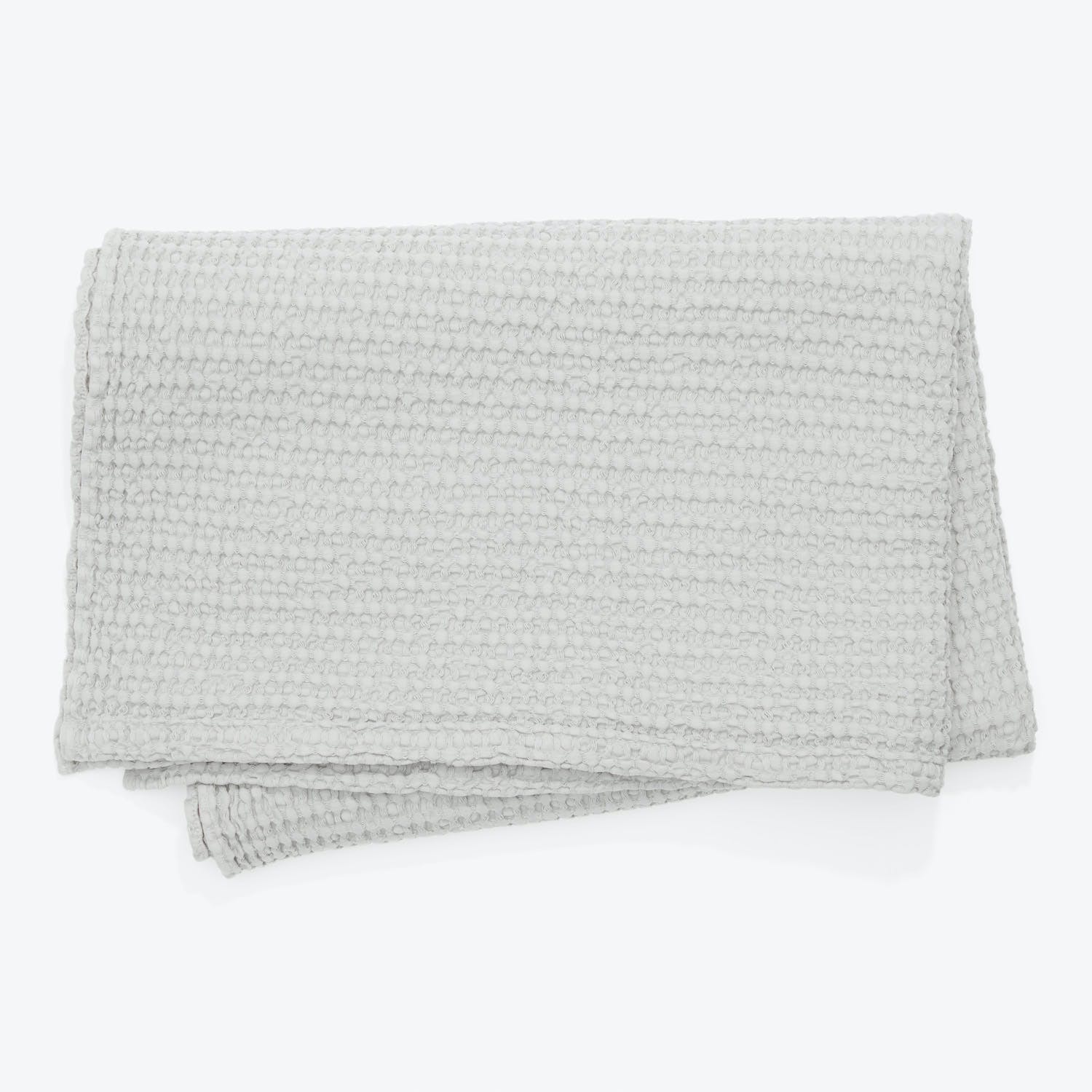 Folded light gray throw with a cozy tactile texture pattern.