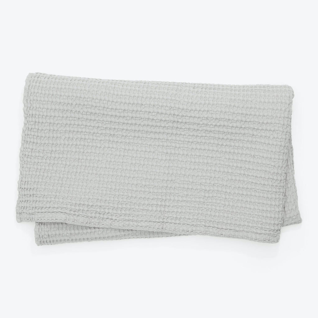 Soft and cozy light gray textured blanket on white background.