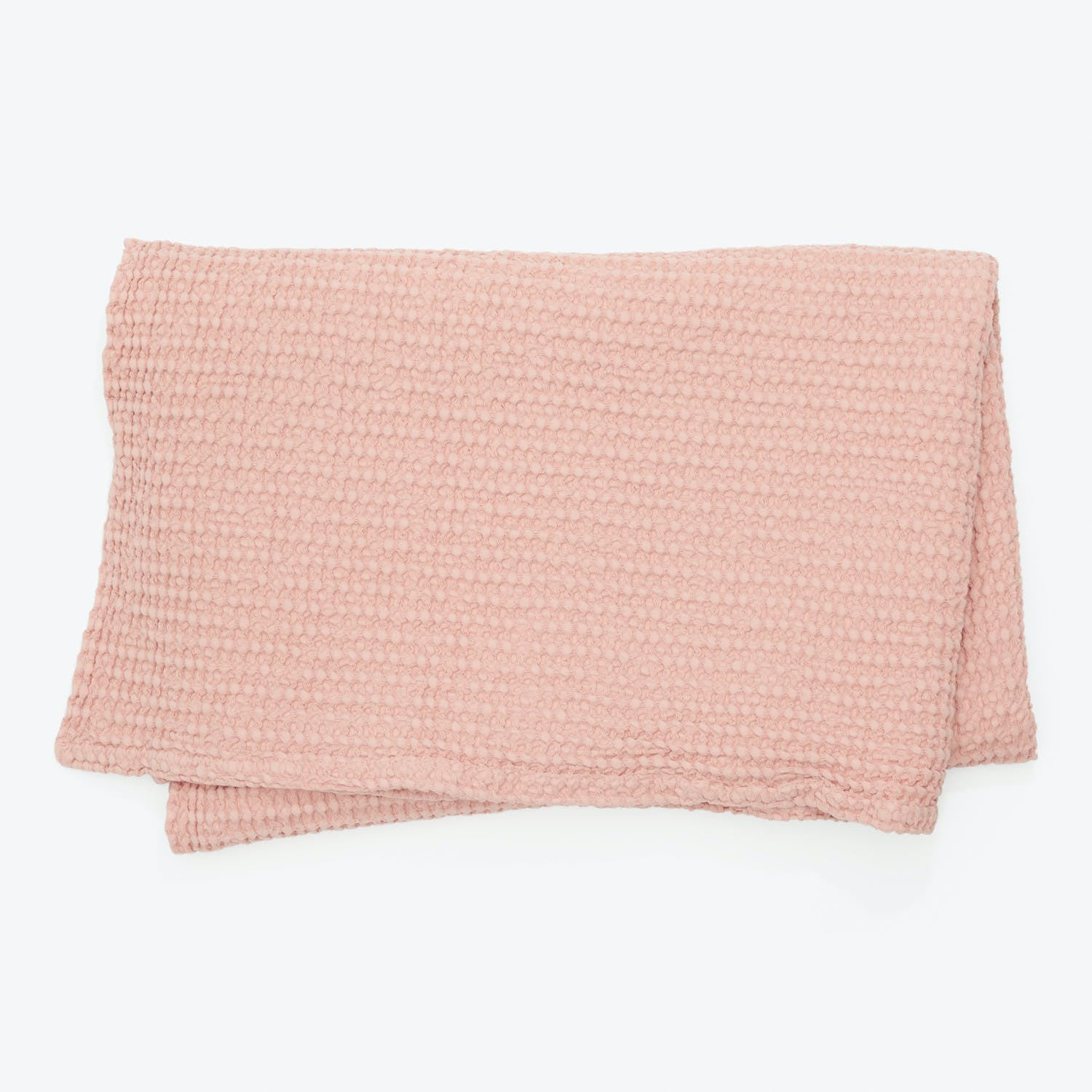 Folded pink towel with textured surface against white background.