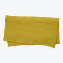 Folded mustard yellow towel with soft textured surface on white background.