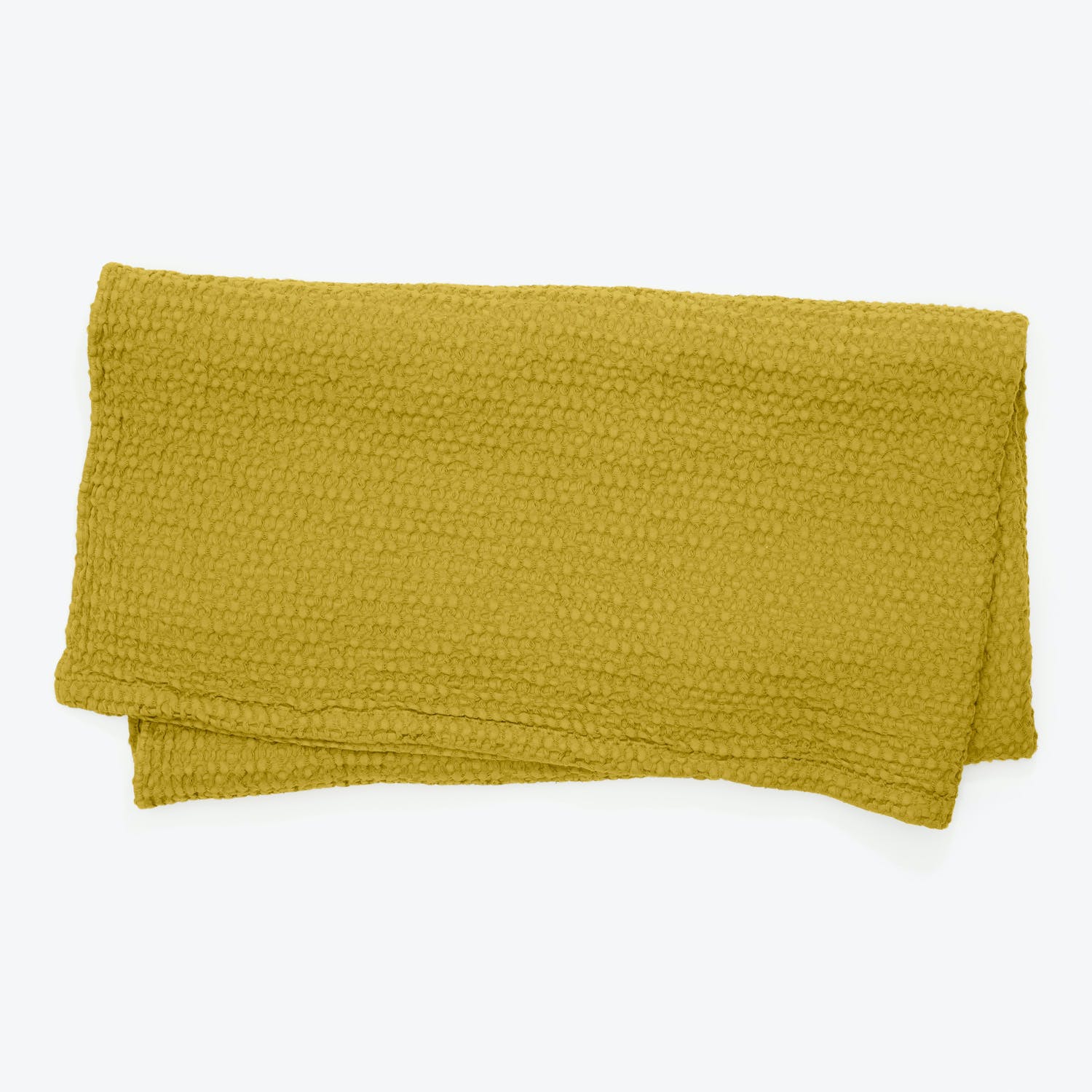 Folded mustard yellow towel with soft textured surface on white background.