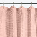 Close-up of a pale pink, textured shower curtain with waffle pattern.