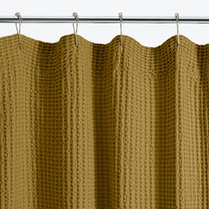 Close-up of a pale pink, textured shower curtain with waffle pattern. - hover