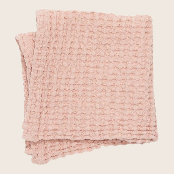 A soft and cozy light pink blanket with a textured pattern.