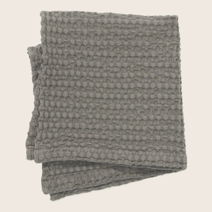 Monochromatic gray throw with raised circular loop pattern, neatly folded.
