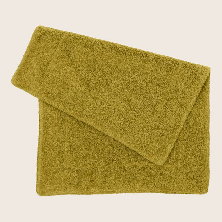 Plush olive green bath towel folded neatly on white background.