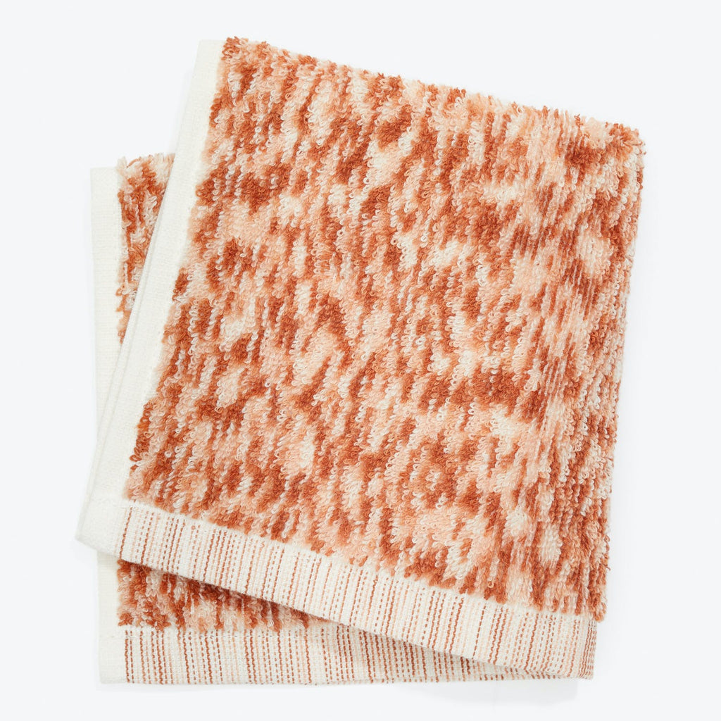 Textured off-white and orange towel with ribbed edge stands out.