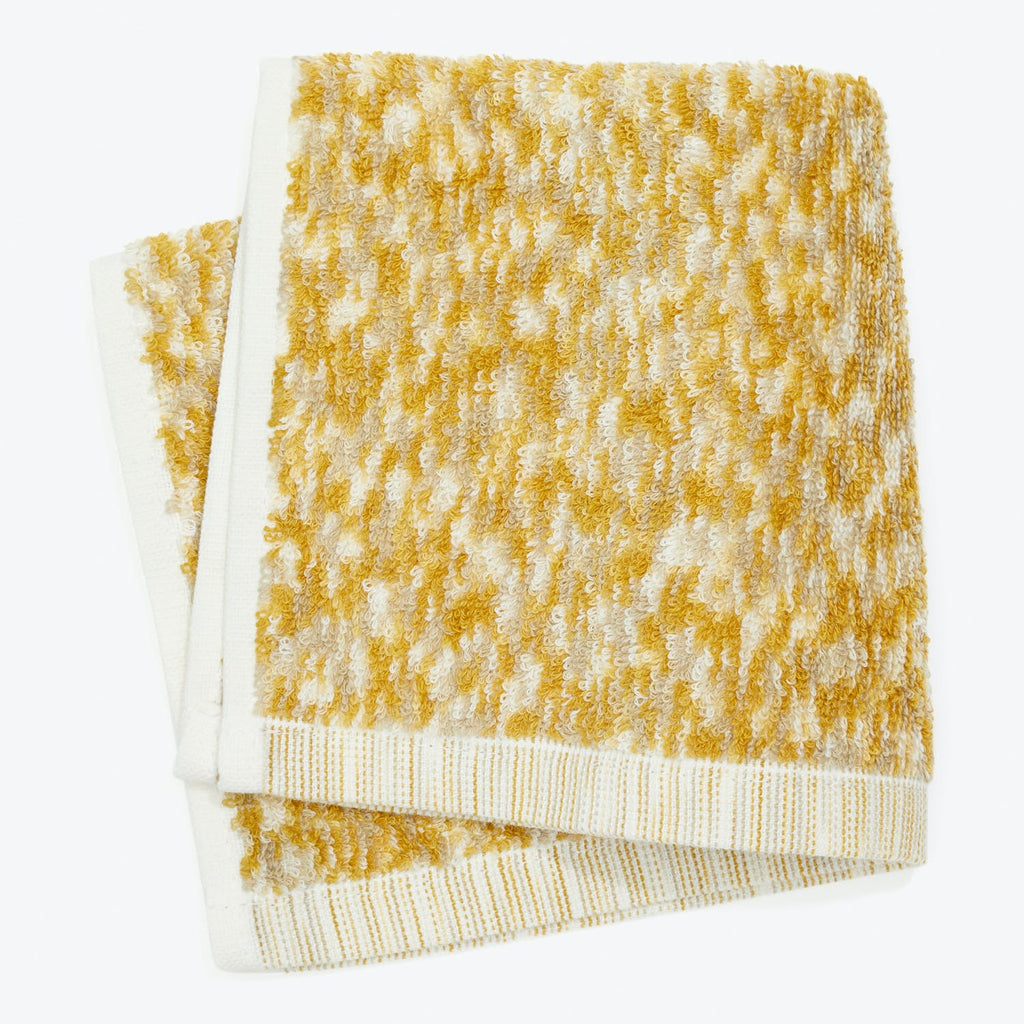 A plush, gold terrycloth towel with white striped binding.