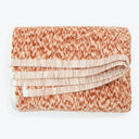 Neatly folded terry cloth towel with textured pattern in peach.