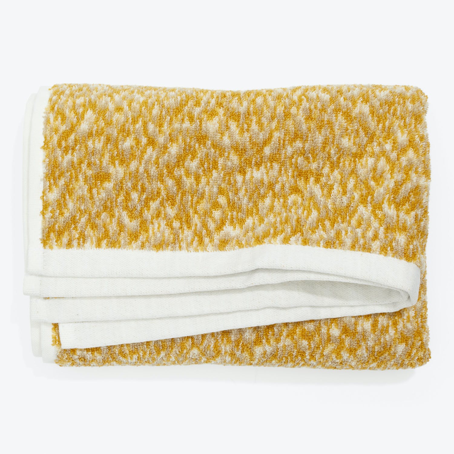 Folded plush towel with white and mustard-yellow patterned border.
