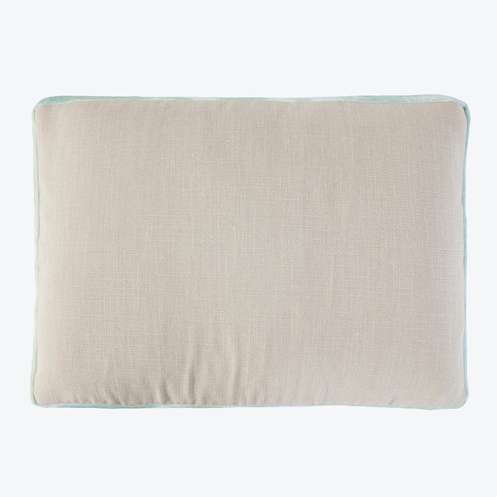 Rectangular pillow with textured fabric in neutral color and contrasting trim.