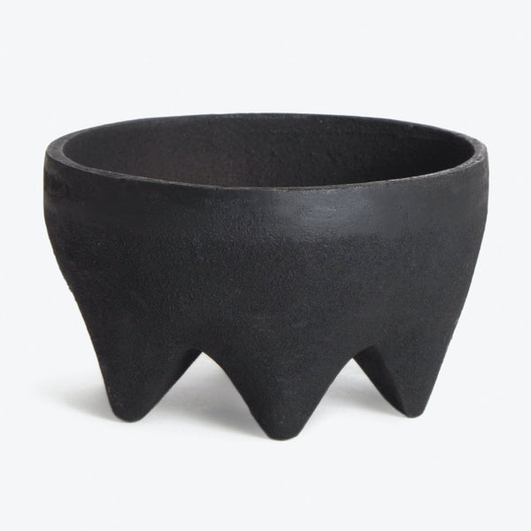 Modern black bowl with triangular leg base showcases artisanal texture.