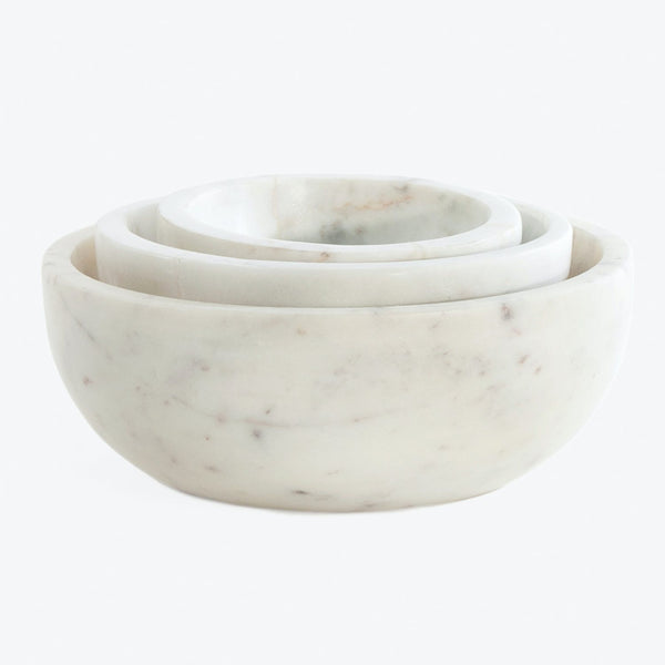 Set of three nested marble bowls with unique veining patterns.