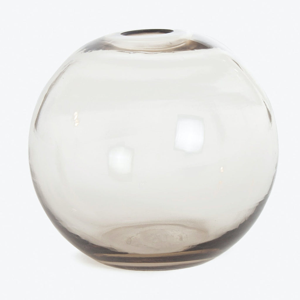 Round, transparent glass vase with smoky tint and reflective surface.