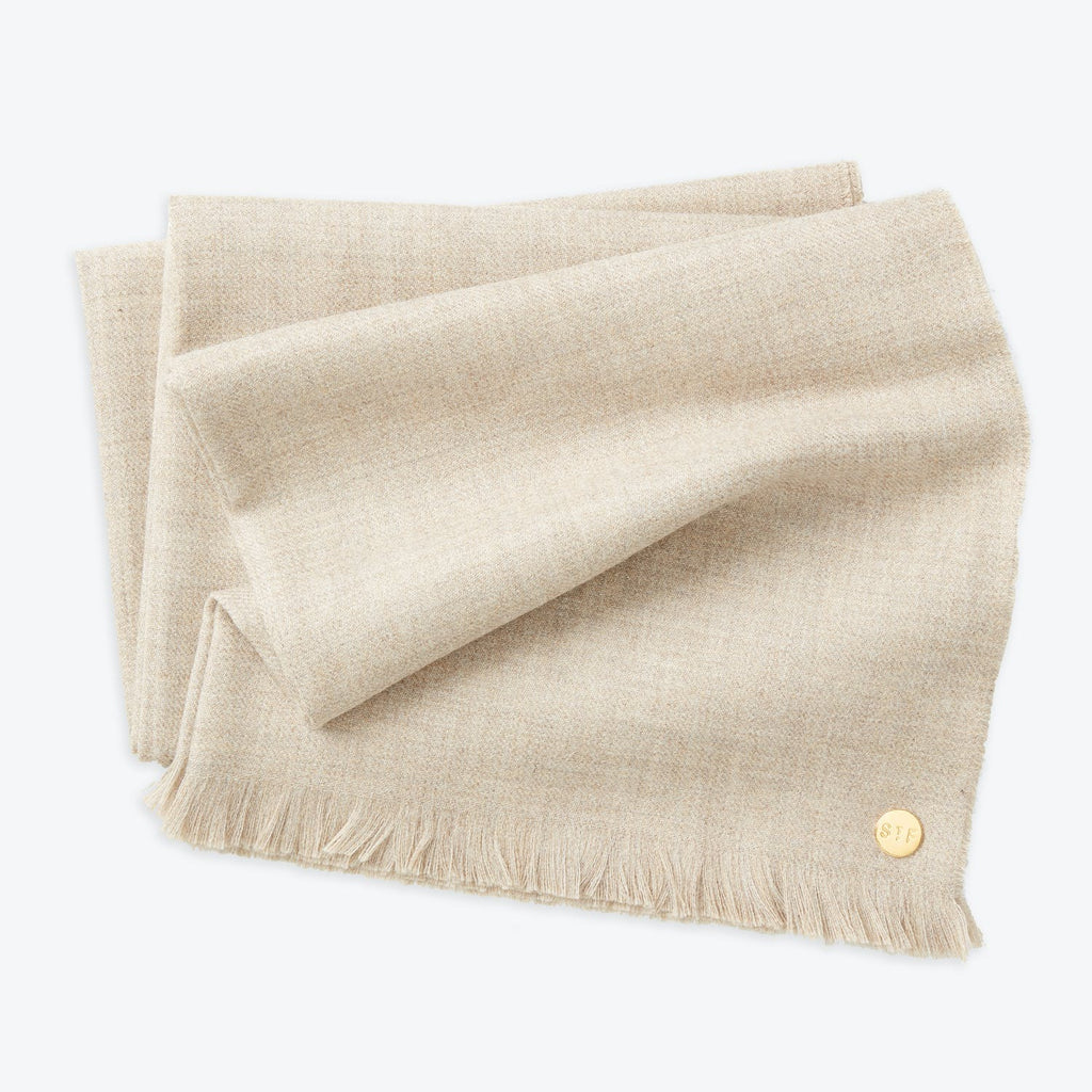 Neatly folded beige fabric with fringe detail and gold button.