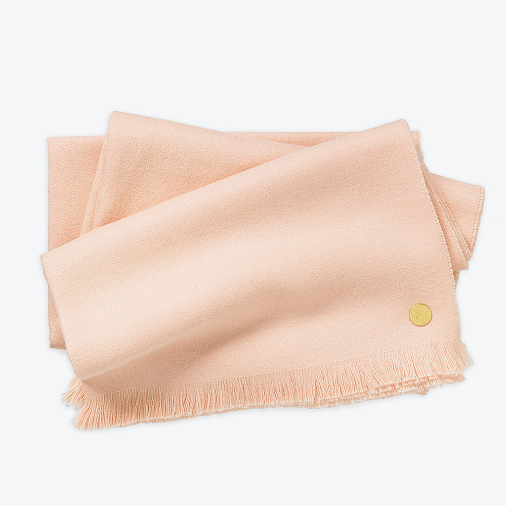 Soft pink fabric with fringe and golden button detail close-up.
