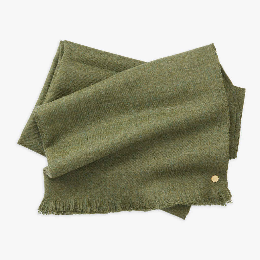 Folded green woolen textile with fringe and metallic embellishment.