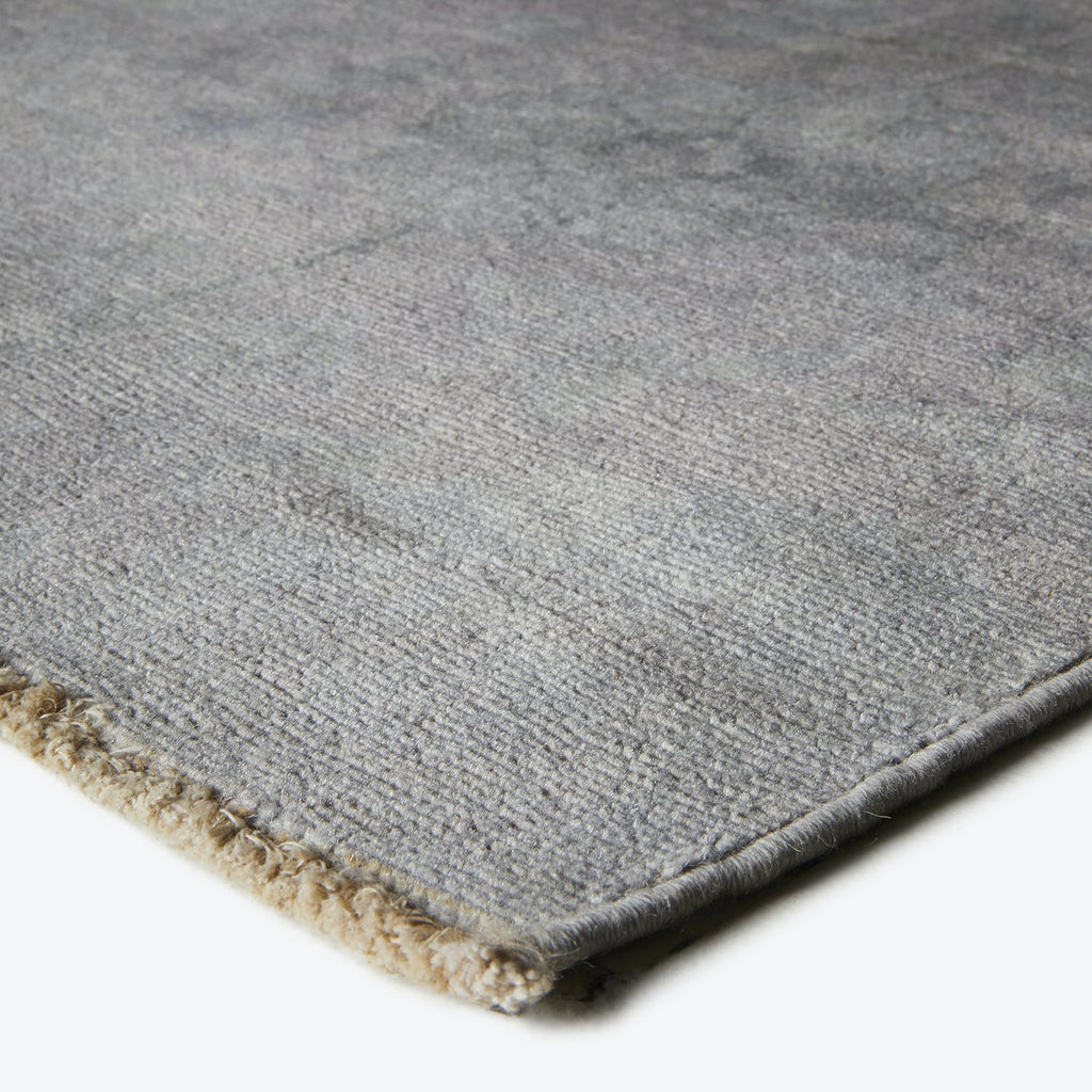 Close-up of a grey textile rug with folded border and texture.