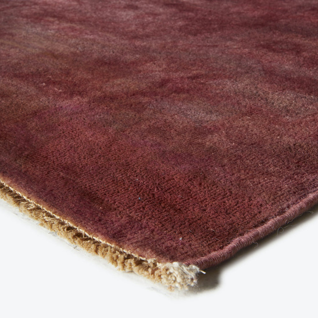 Close-up of plush, burgundy rug with varied gradient color.