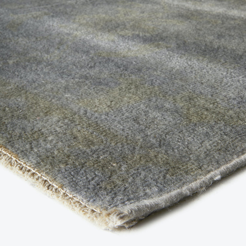Close-up of a soft, dense grey rug with geometric pattern.